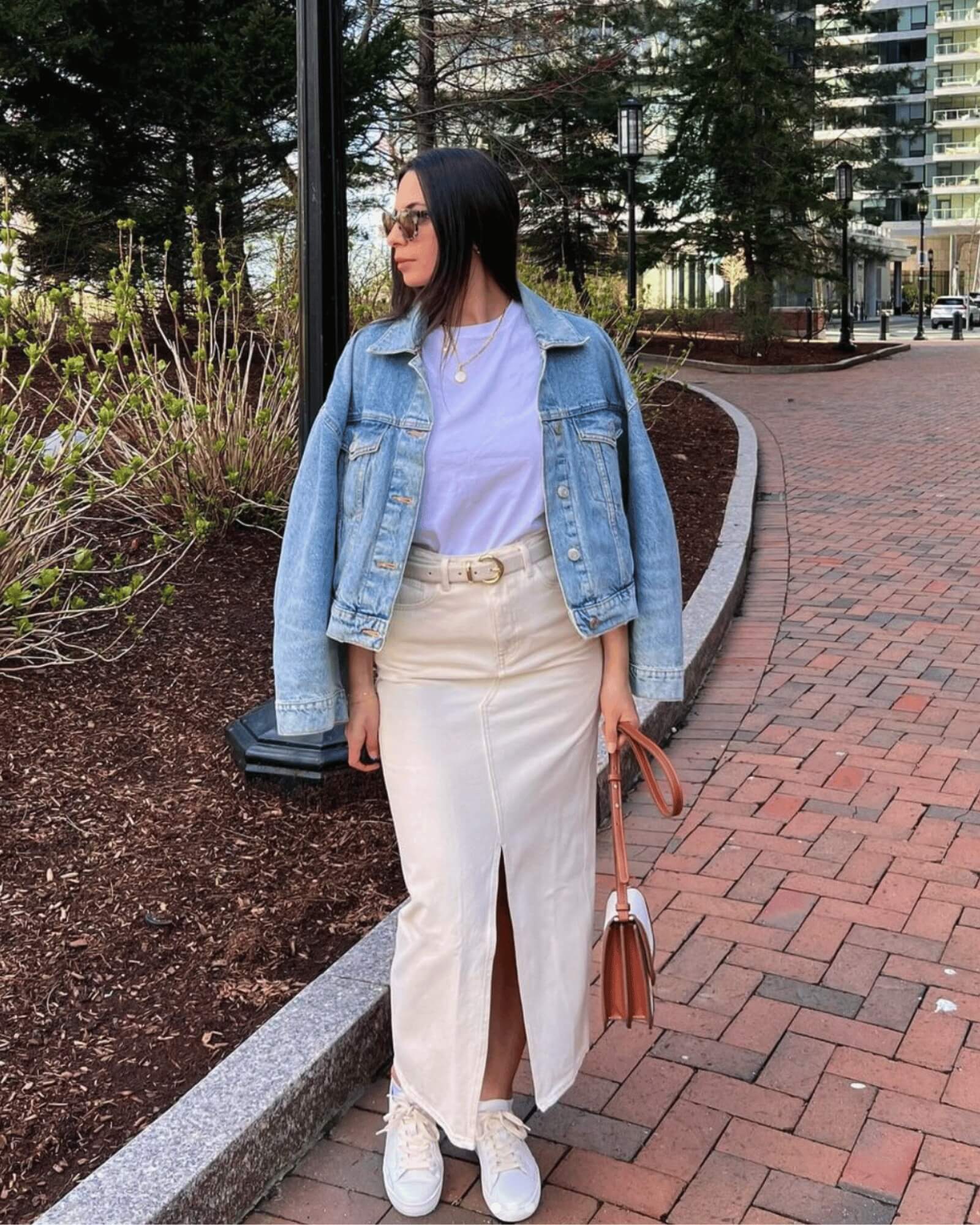 woman looking away from camera wearing white ibiza sneakers with a denim jacket over her shoulders