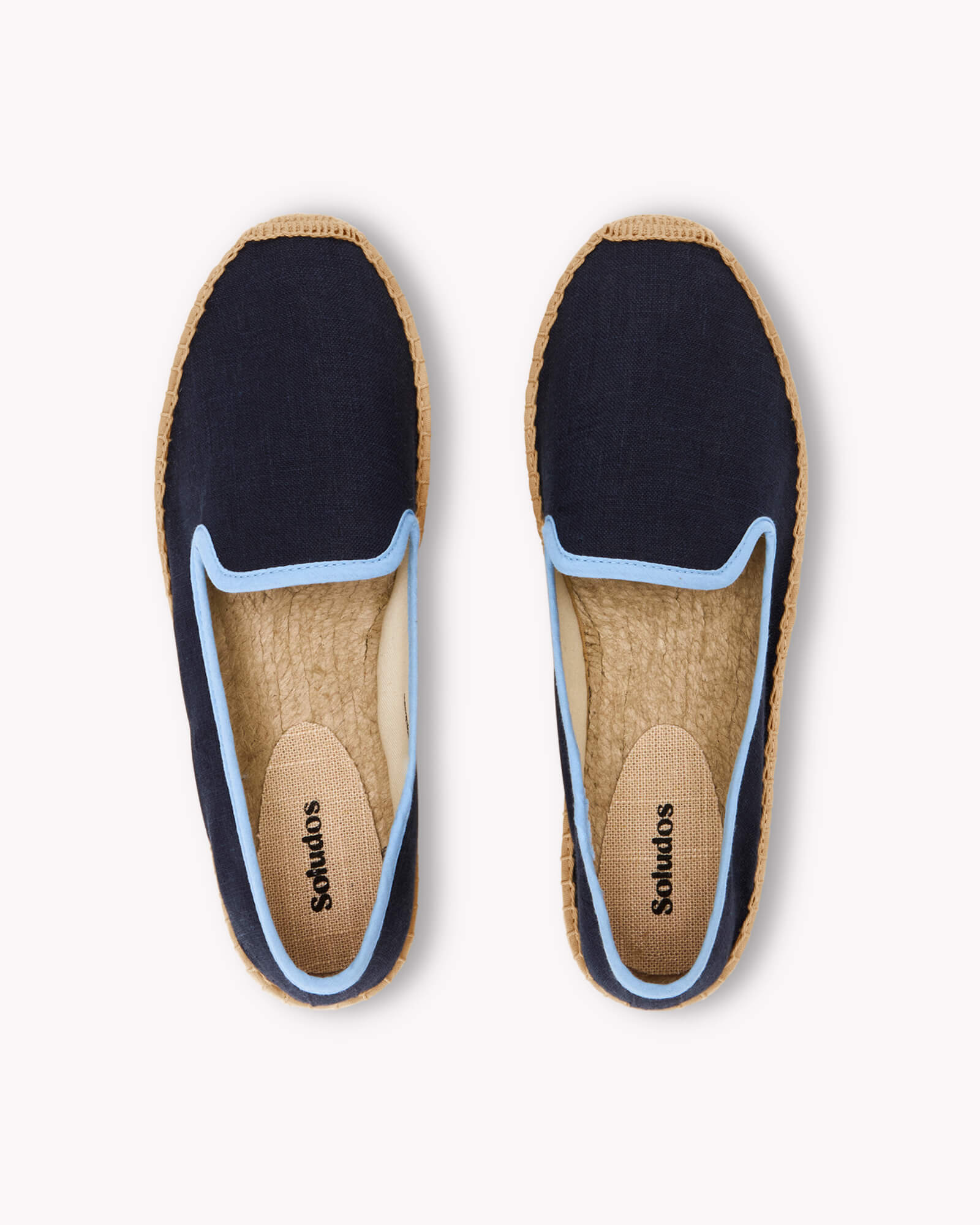 Women's navy espadrille shoes with light blue piping on gray background