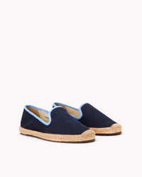 Women's navy espadrille shoes with light blue piping on gray background