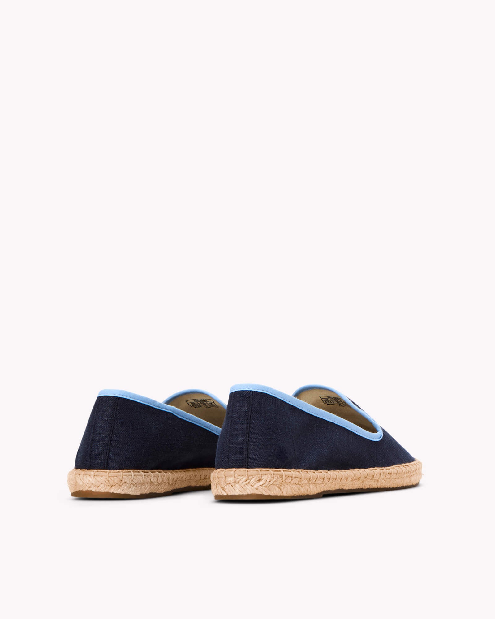 Women's navy espadrille shoes with light blue piping on gray background