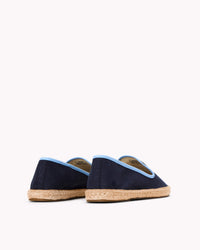 Women's navy espadrille shoes with light blue piping on gray background